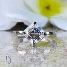 a diamond ring sitting on top of a table next to a white flower and an orchid