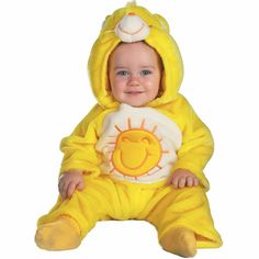 a baby dressed in a yellow bear costume sitting on the floor wearing a sunflower onesie