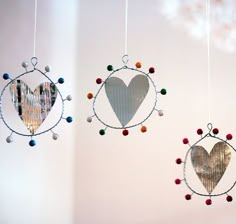 three heart shaped mirrors hanging from strings in a room with white walls and flooring