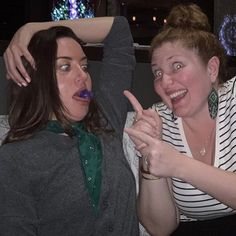 two women posing for the camera with their fingers up