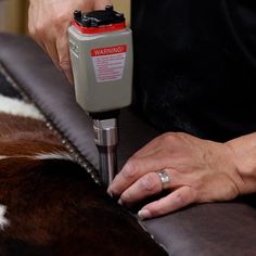 a woman is using a machine to fix a cow skin area on a couch in the living room