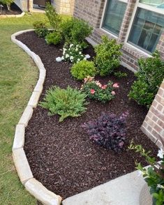 a flower bed in front of a brick house