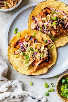 two tacos on a plate with limes, onions and other food items next to them