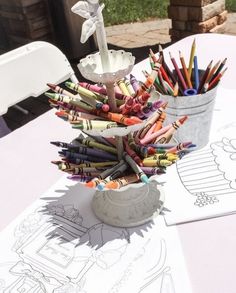 an arrangement of crayons in buckets on top of a table with paper