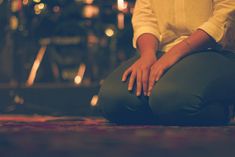 a woman sitting on the ground with her hands in her lap