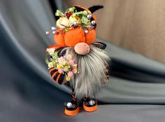 an orange and black stuffed animal with flowers on it's head, sitting on a gray surface