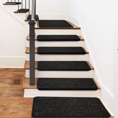 black carpeted stair treads leading up to the first floor in a home with white walls