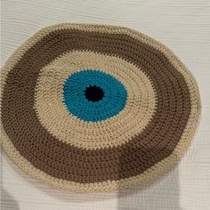 a crocheted round rug with an eye on the center in brown and blue