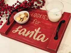 a red tray with cookies and a bowl of nuts on it next to a glass of milk