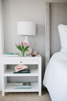 an instagram page for gray bedroom with pink flowers on the nightstand and white bedding