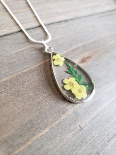 Beautiful real dried yellow garden flower pendant made from preserved yellow flower petals in resin in a vibrant silver teardrop. Elegant yellow and green flower necklace on 925 sterling silver plated stainless steel necklace chain. Natural dried flower jewelry piece ♥ Please note that every flower is different as found in nature Be sure to check out the NECKLACE section at EarringsbyLCreations for all kinds of necklaces available! https://www.etsy.com/shop/EarringsByLCreations?section_id=250342 Yellow Sterling Silver Flower Jewelry, Sterling Silver Necklaces With Pressed Flowers, Yellow Necklace With Birth Flower Pendant, Yellow Birth Flower Pendant Necklace, Teardrop Jewelry With Pressed Flowers, Yellow Pressed Flowers Jewelry, Silver Sterling Silver Necklace With Pressed Flowers, Silver Flower Pendant Jewelry With Pressed Flowers, Handmade Yellow Drop Jewelry