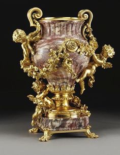 a gold and marble vase with cherubs on it