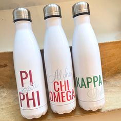 three white water bottles sitting on top of a wooden shelf with the words phi, hawaii, and kapa written on them