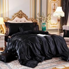 a bed with black sheets and pillows on top of it in a room filled with furniture