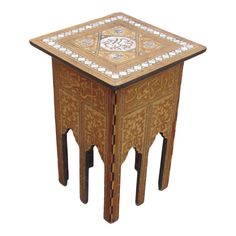 a small wooden table with an intricate design on the top and bottom, sitting against a white background