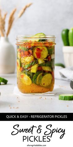 a jar filled with pickles sitting on top of a table next to other vegetables