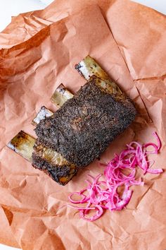 a piece of meat sitting on top of a table next to red onions and a knife