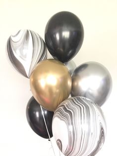 a bunch of black, white and gold balloons