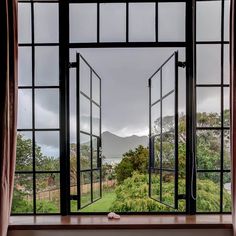 an open window looking out onto a lush green field with mountains in the back ground