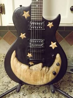 a black guitar with gold stars on it sitting on a counter next to a sink