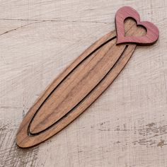 a wooden cutting board with a heart cut out of it sitting on a piece of wood