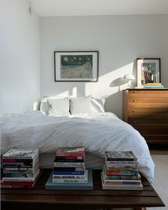 a bed sitting in a bedroom next to a dresser with books on top of it