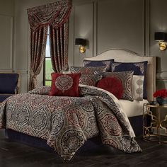 a bed with red and blue comforters in a bedroom next to a window,