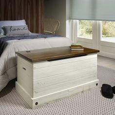 a bed room with a neatly made bed and a wooden trunk on the floor next to it