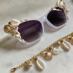 Translucent white cat-eye framed sunglasses embellished with cowry shells, coral branch beads, metallic gold scallop shells, pearls, rhinestones, and beaded starfish appliqués. Eat your heart out, Esther Williams! FINAL SALE. Get 35% off 1 item with code 1FOR35OFF Get 50% off 2 items with code 2FOR50OFF Get 75% off 3+ items with code 3+FOR75OFF Elegant White Sunglasses For Vacation, Elegant White Sunglasses For The Beach, Elegant Pearl White Shell For Beach, Elegant White Shell For Beach, Pearl White Shell For Beach, White Glass Beach Jewelry, Elegant Shell For Summer Vacation, Elegant Summer Shell For Vacation, Elegant White Beaded Shell