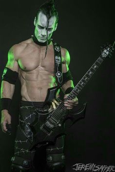 a man with green paint on his face holding a guitar