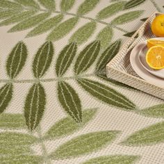 two oranges are sitting on a plate with green leaves