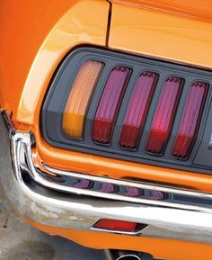 an orange mustang with red tail lights and chrome rims