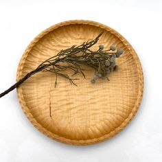 a wooden plate with some dried herbs on the top and one branch in the middle