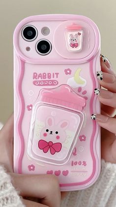 a person holding up a pink phone case with a bear on the front and a cup in the back