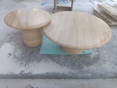 two wooden stools sitting next to each other on top of a cement floor in front of boxes