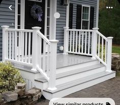 a porch with white railings and steps leading up to the front door on a blue house