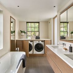 a large bathroom with two sinks, a tub and a washer dryer in it