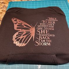 a black shirt with a pink butterfly on it and some words printed on the back