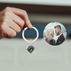 a hand holding a keychain with an image of a man and woman on it