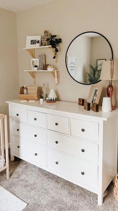 a baby's room with a dresser, mirror and crib in the corner