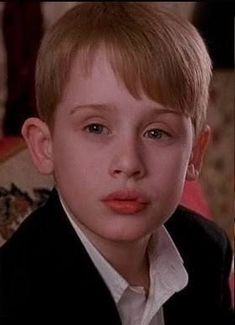 a young boy in a suit and tie looking at the camera with an intense look on his face