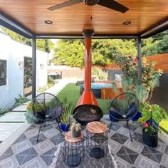 an outdoor living area with chairs, tables and a fire place in the middle of it