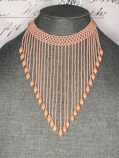 an orange necklace with beads and chains on top of a mannequin's head