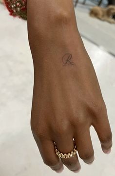 a woman's hand with a small tattoo on her left wrist and gold chain bracelet