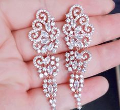 A beautiful pair of bridal earrings that is sure to make a bold statement on your Wedding Day! Adorned with glowing cubic zirconia that capture the light from every angle with a perfectly translucent appeal, the earrings are rhodium/rose gold plated for a bright finish which enhances the intricate detailing and conveys a modern take on old elegance. Length of the earring is 2.4" (approx. 6.1cm); Width: 0.7" (approx. 1.8cm); Weight: 12g. Available in Silver and Rose Gold finishes. To make your ch Wedding Earrings Silver, Cubic Zirconia Bridal Earrings, Silver Earrings Wedding, Bridal Belt, Bridal Bracelet, Bridal Tiara, Bridal Jewelry Sets, Bridal Necklace, Bridal Hair Accessories