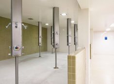 an empty public restroom with urinals and tiled walls on either side of the stalls