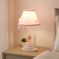 a lamp that is sitting on top of a table next to a bed with pillows