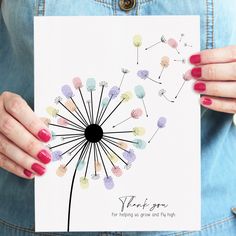 a woman holding up a card with a dandelion design on it and the words thank you