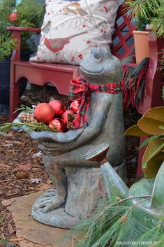 a statue of a frog with ornaments in it's hands sitting on a bench