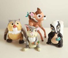 small figurines of various animals sitting on a table together, including an antelope, squirrel, cat and mouse